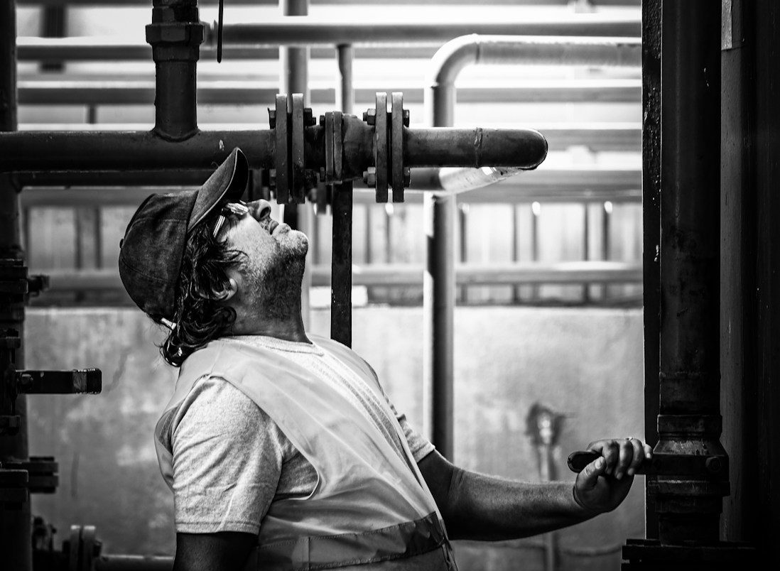 A worker inspects industrial pipes and valves