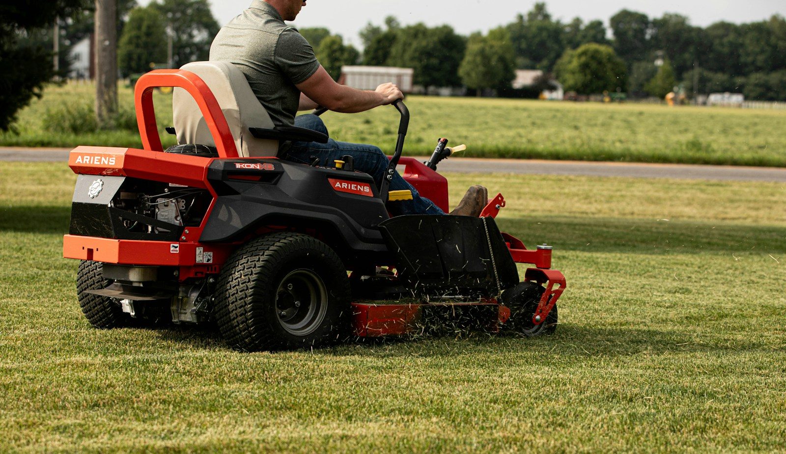 A man mows the lawn with a riding mower