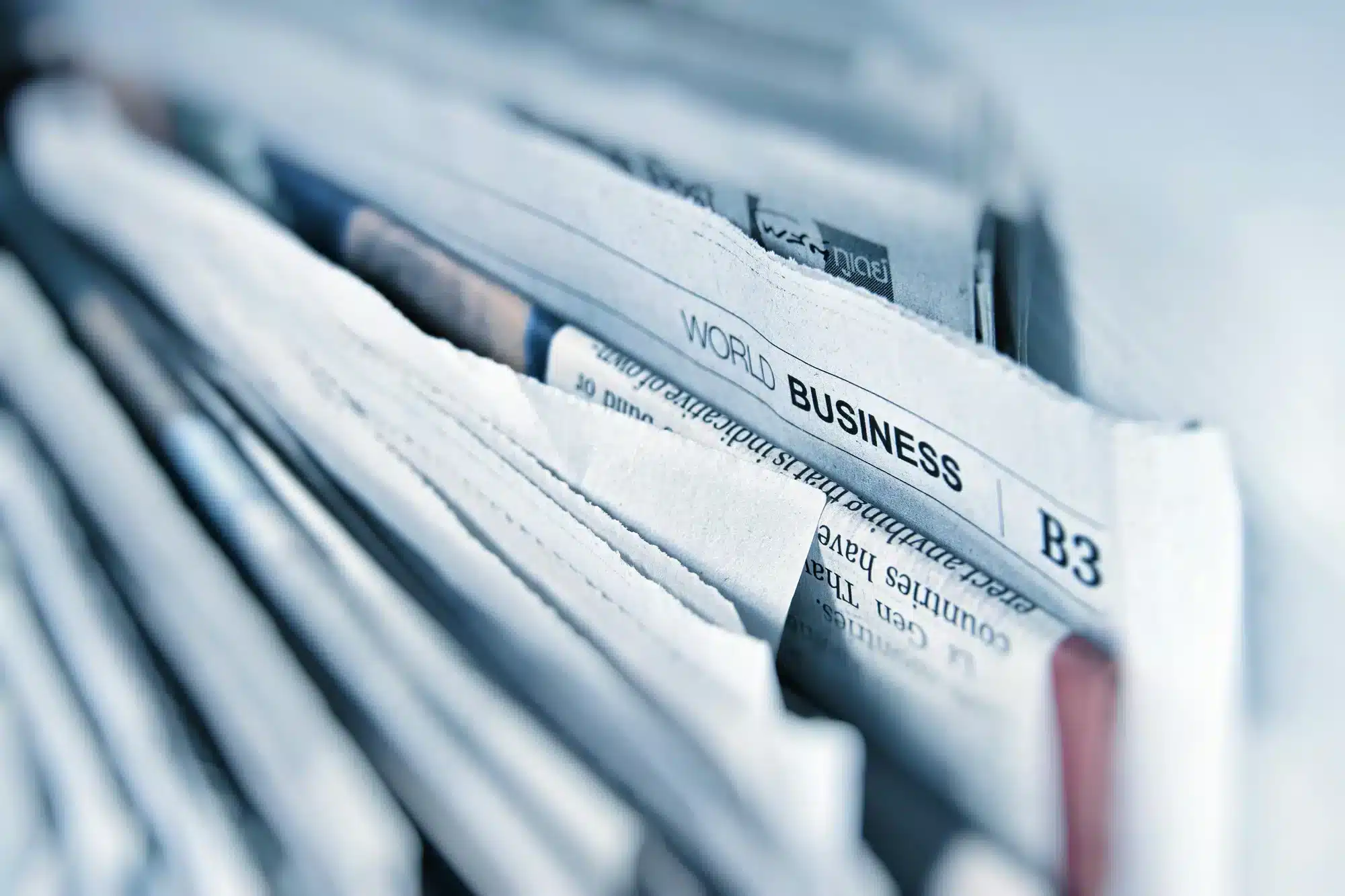 Close-up of a stack of newspapers with a World Business headline on the front page.