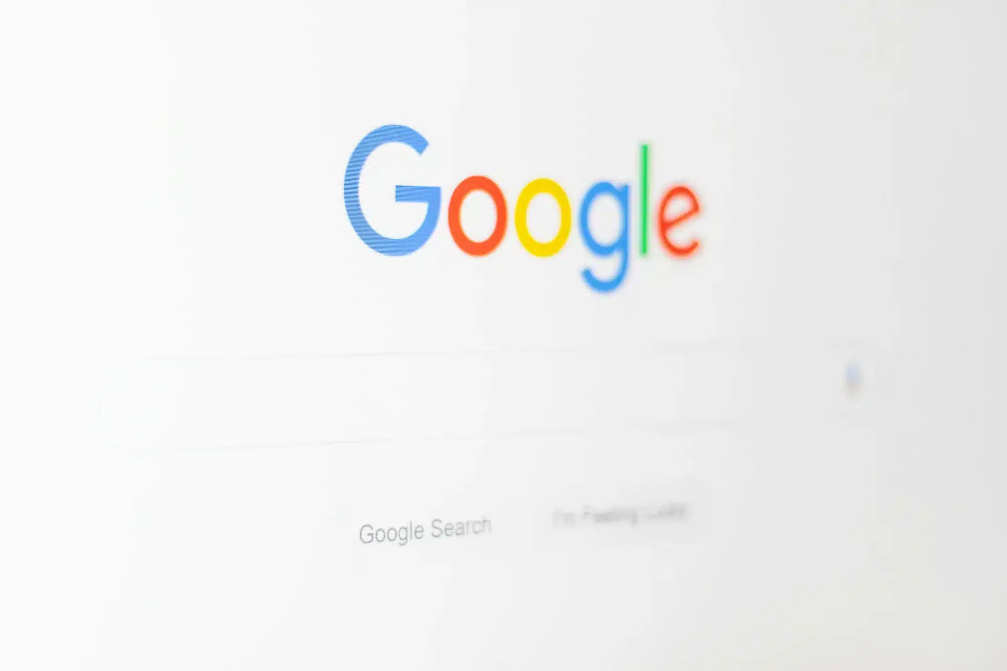 Google logo in multicolored letters on a white background with a faint search bar below.