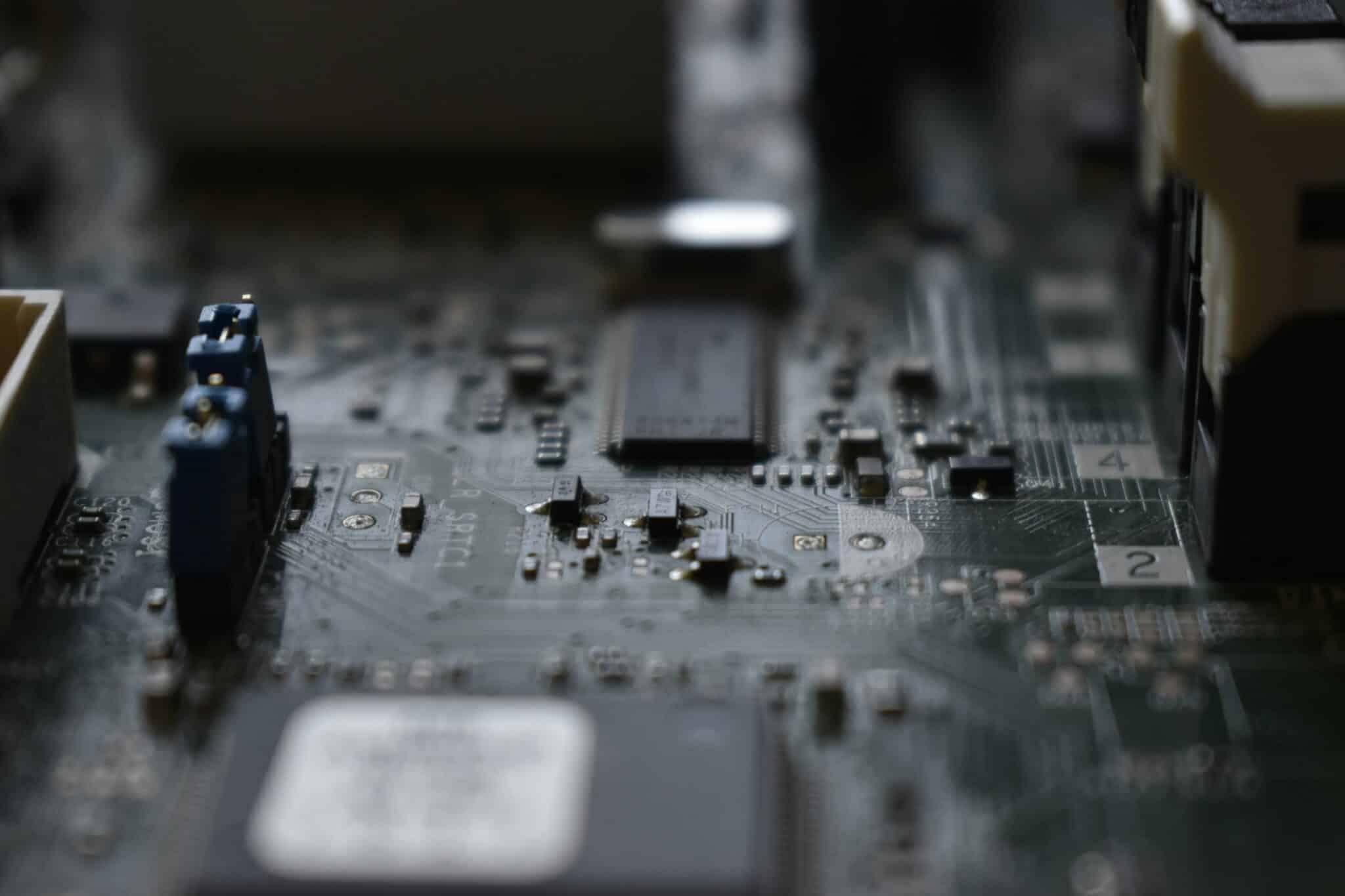 Close-up of a computer motherboard showing a central socket, blue terminal blocks on the left, and many tiny surface-mount components.