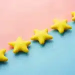 Five yellow star-shaped objects arranged diagonally on a pink and blue split background.