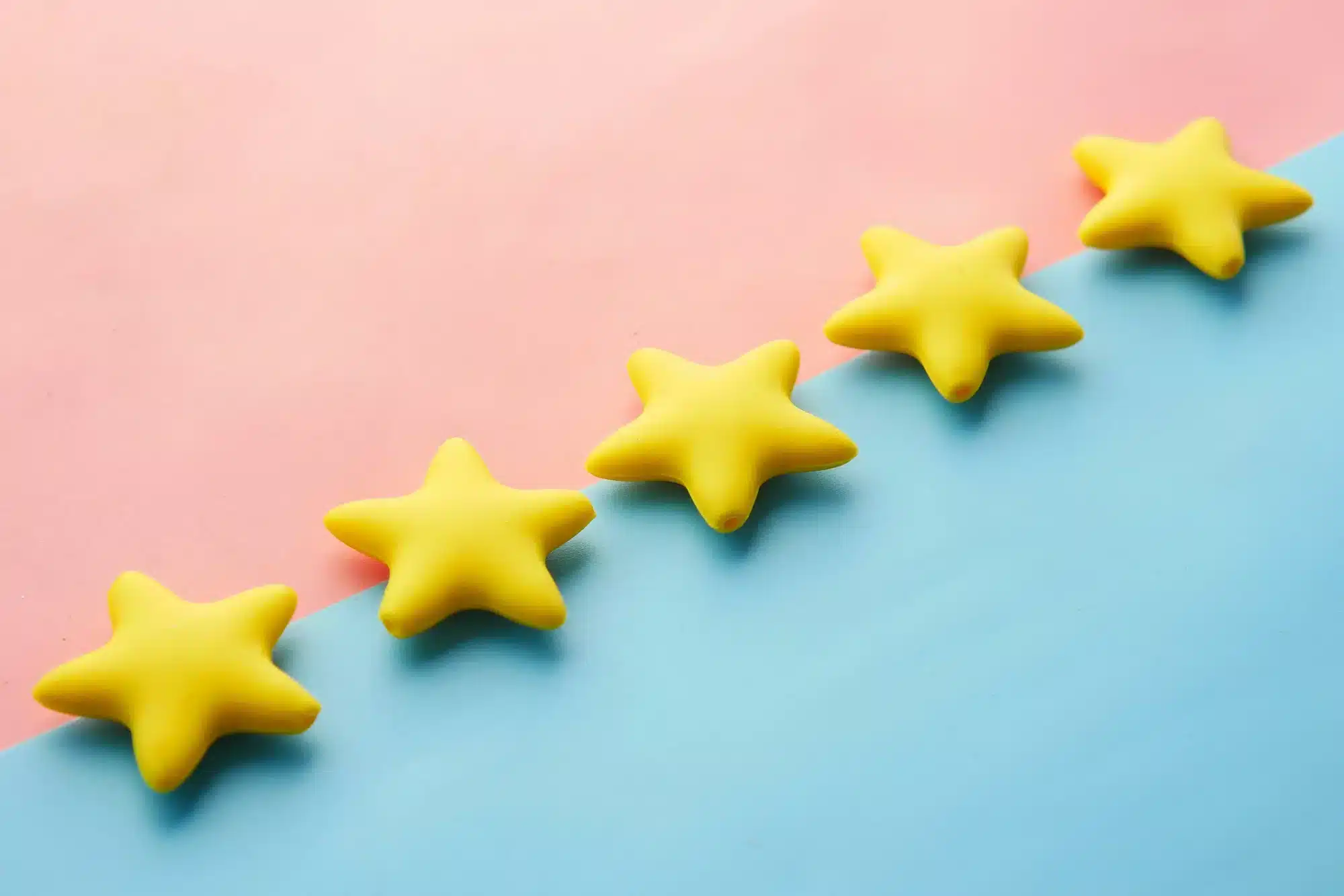 Five yellow star-shaped objects arranged diagonally on a pink and blue split background.